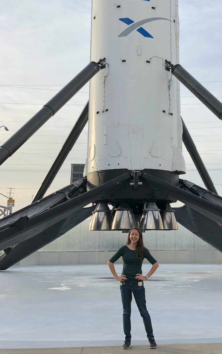 Dawn Andrews standing beneath a booster rocket at SpaceX