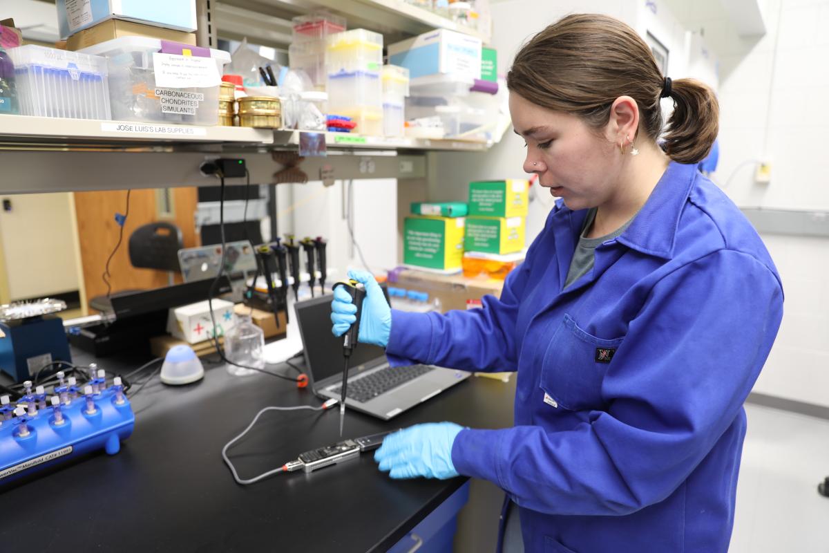 student uses a pipet to place bacteria on sequencing device