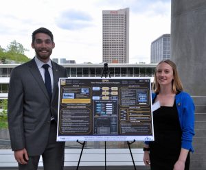 A male and a femal student stand next to their poster at the ASDL EAB