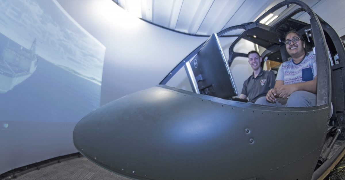 Bob Walters and Vinodhini Comandur sitting in the helciopter simulator