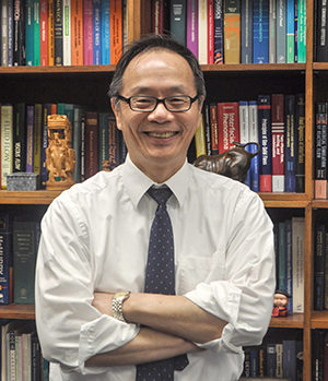 Vigor Yang standing in front of his bookcase